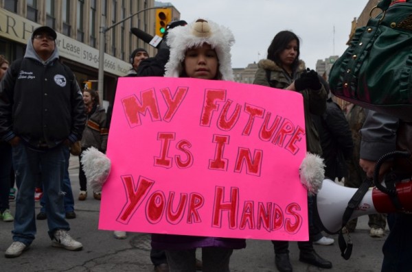 child holding a sign says "my future is in your hand"