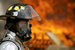 A firefighter stands in front of a distant fire.