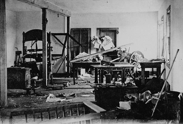 Printing presses have been destroyed in a ransacked room.
