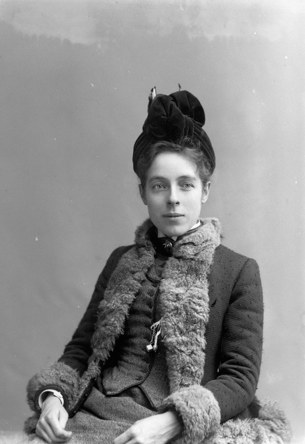 Photo portrait of a woman wearing a fur-lined coat and a velvet hat.