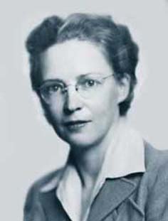 A headshot of a woman with glasses and a collared shirt looking intensely at the camera.