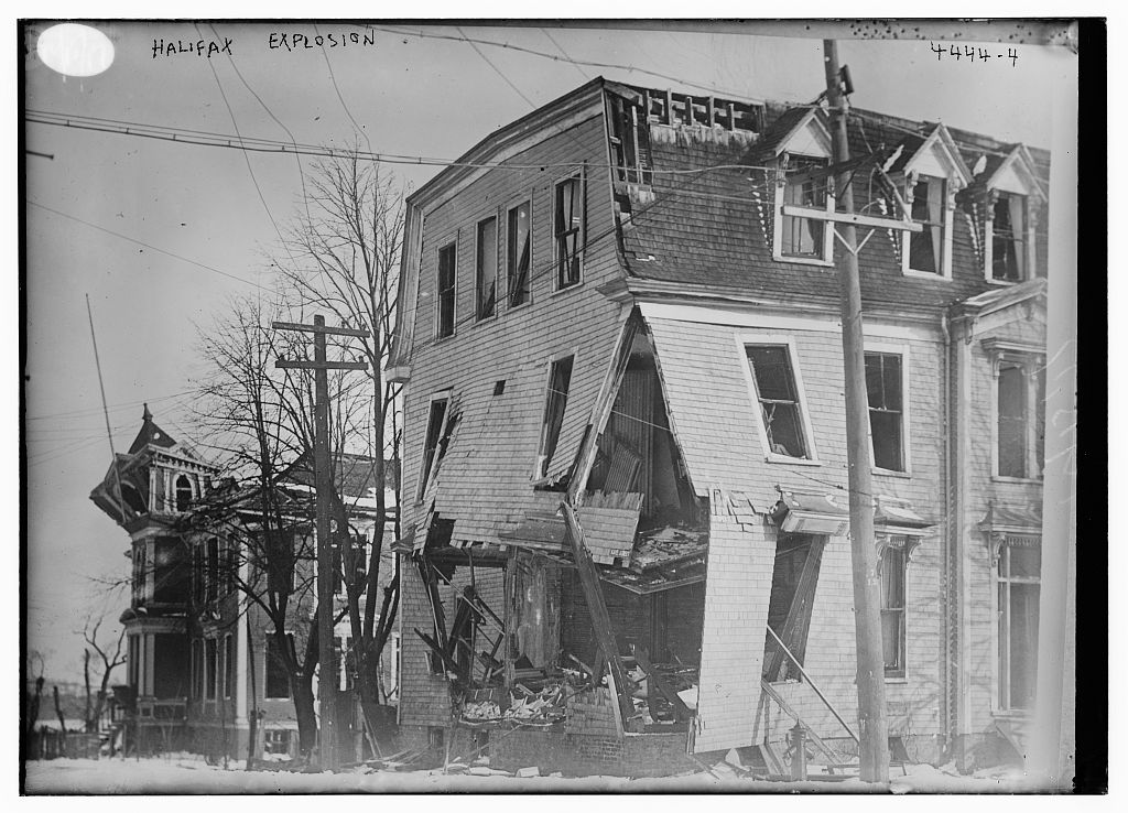 A three-story building has a hole at the corner where the second level is collapsing.