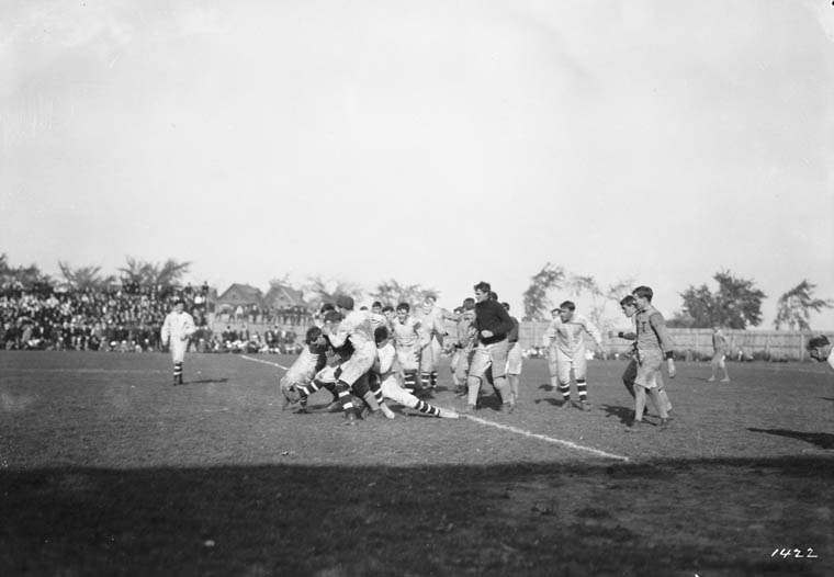 Men tackle each other and tussle on a football field.