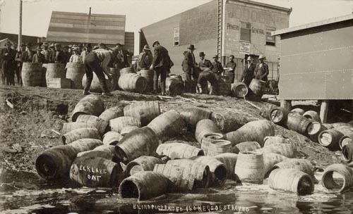 Barrels are scattered all over the ground. Men in suits look on.