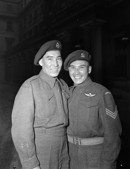 Two smiling young men wearing military uniforms and berets.