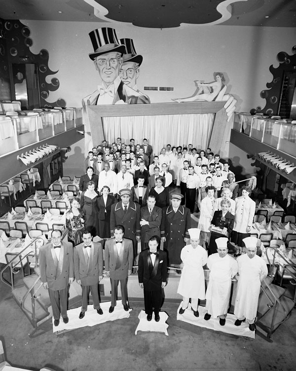 Restaurant dining room full of servers, chefs, and military officers.