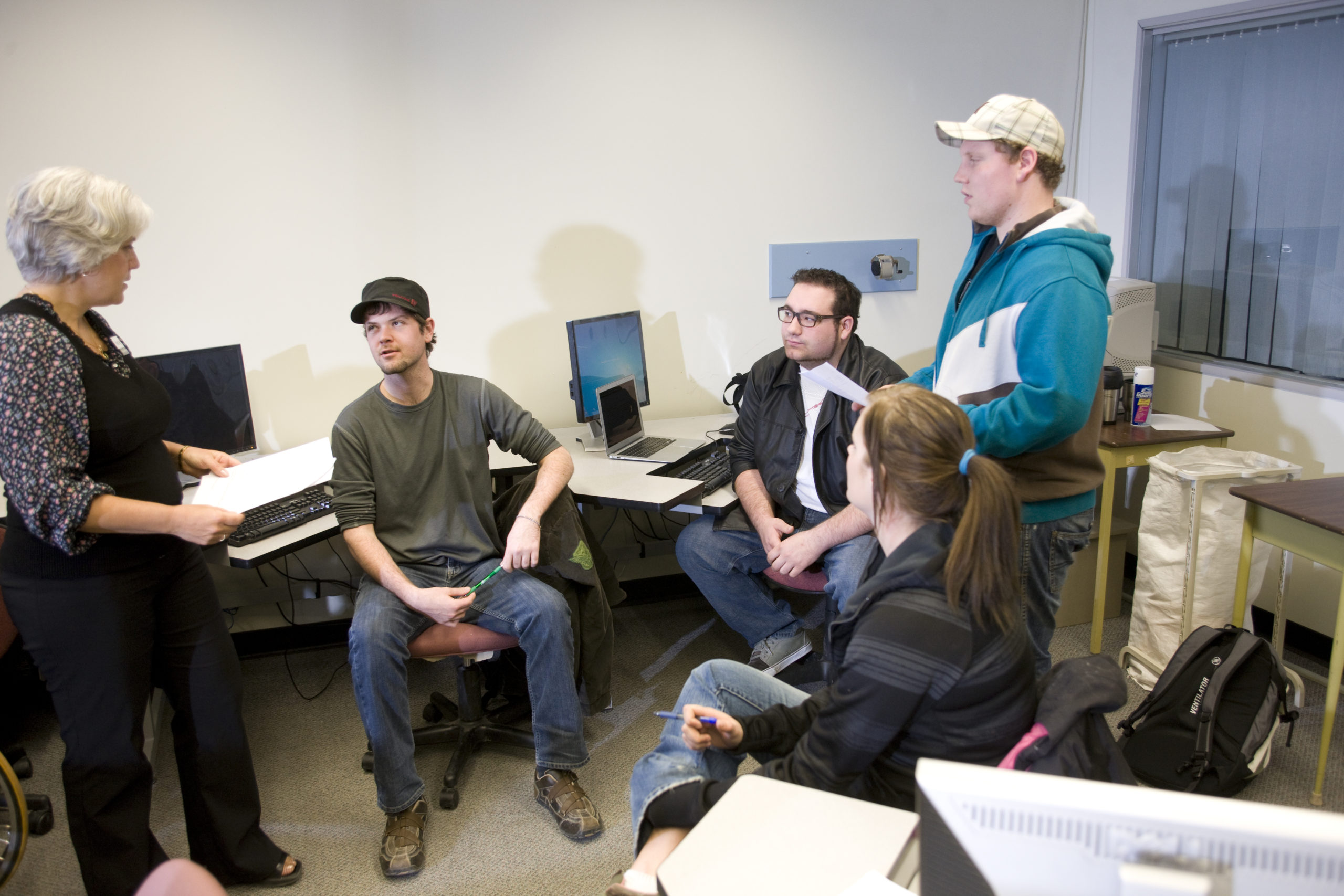 A group of students talking a computer lab