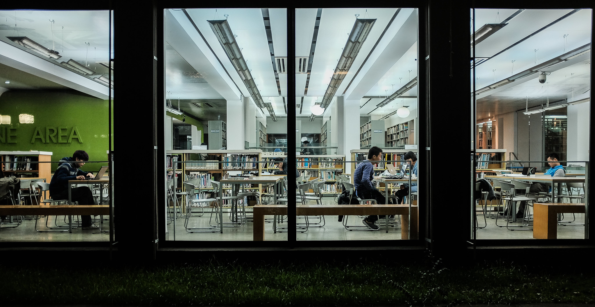 Students studying at large tables in a library late at night