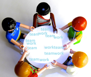 A group of toys gathered around a table. The table has "team work" written all over it