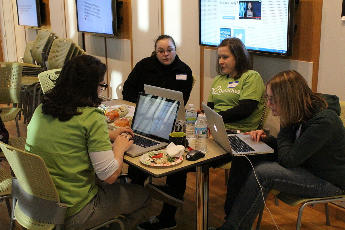 A group of people gathered around a table on laptops.
