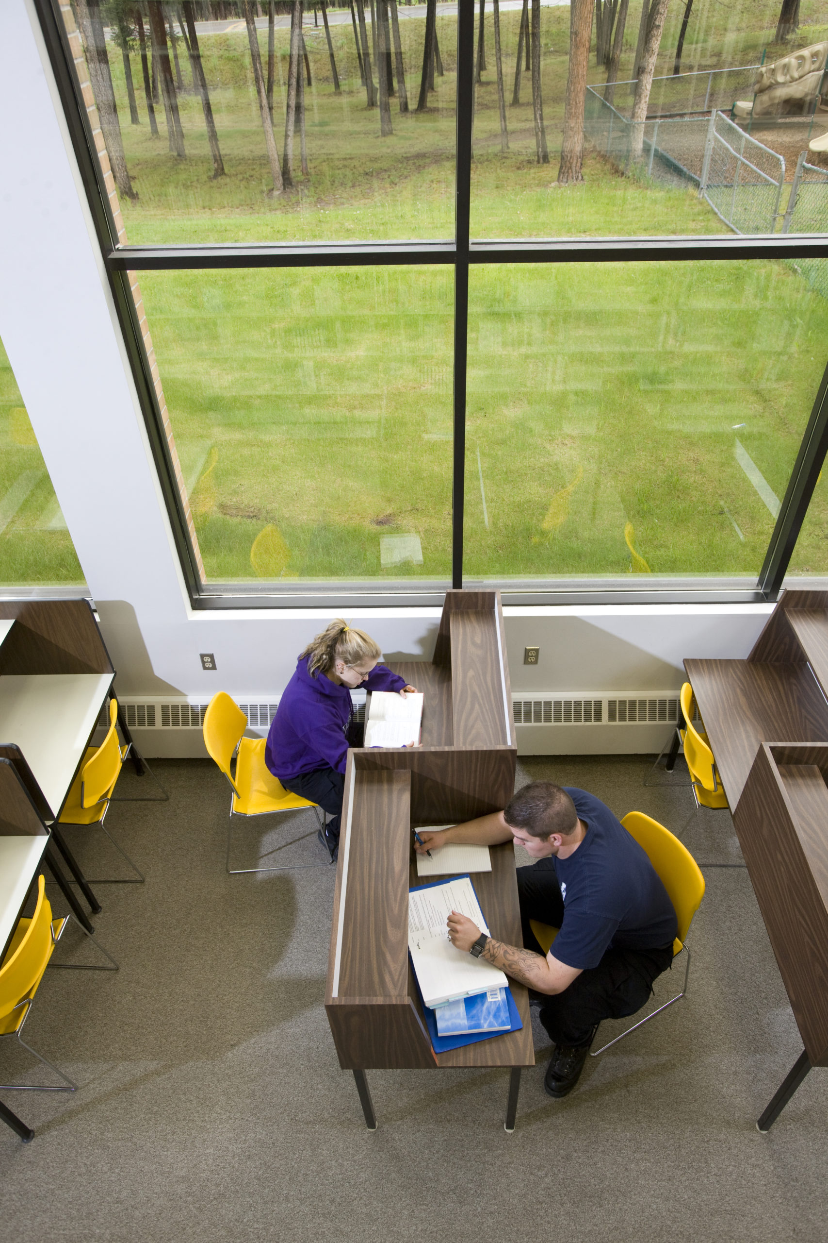 Students study an desks near big windows in the library