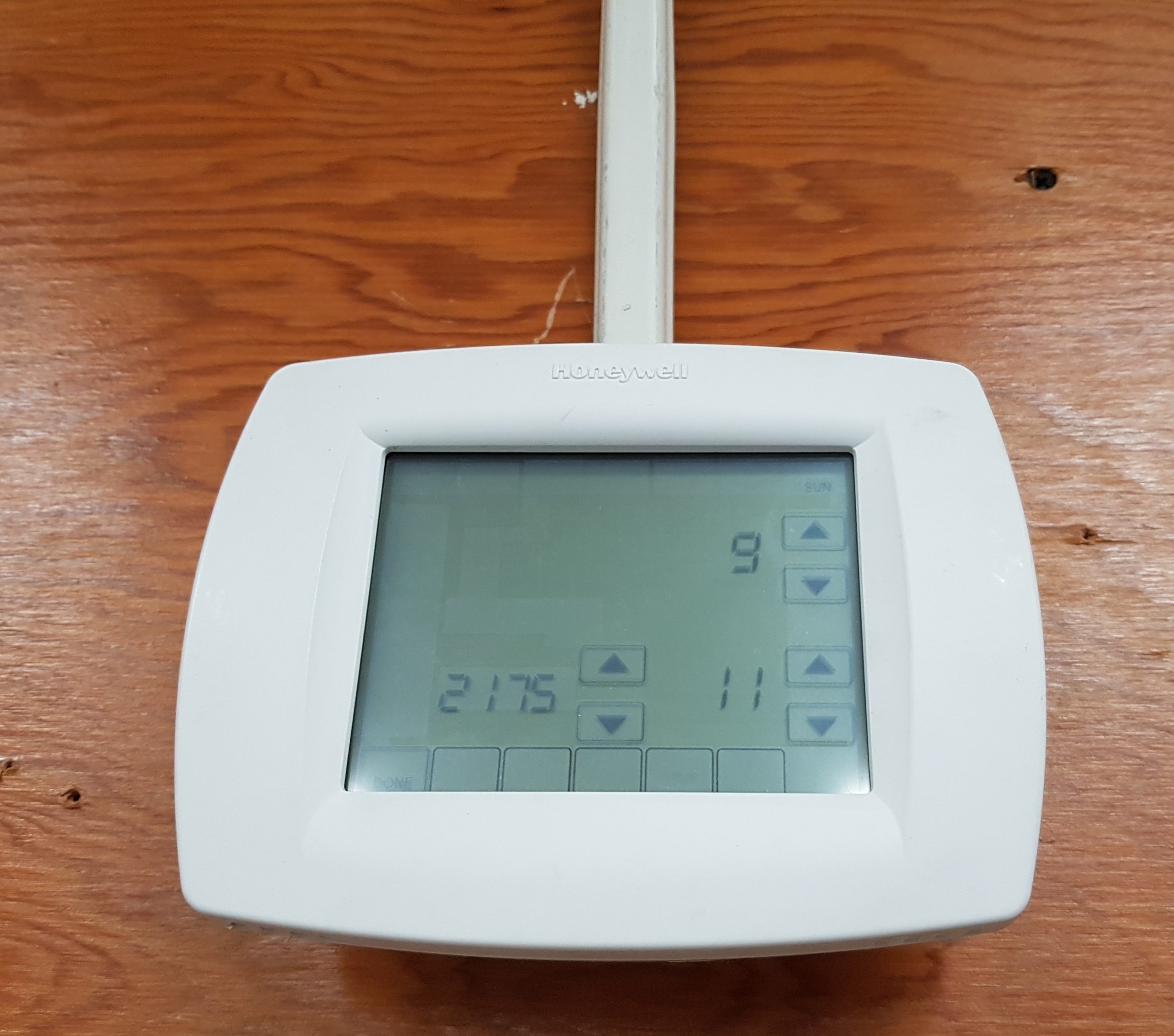 An electronic thermostat with a touch screen attached to the wall.