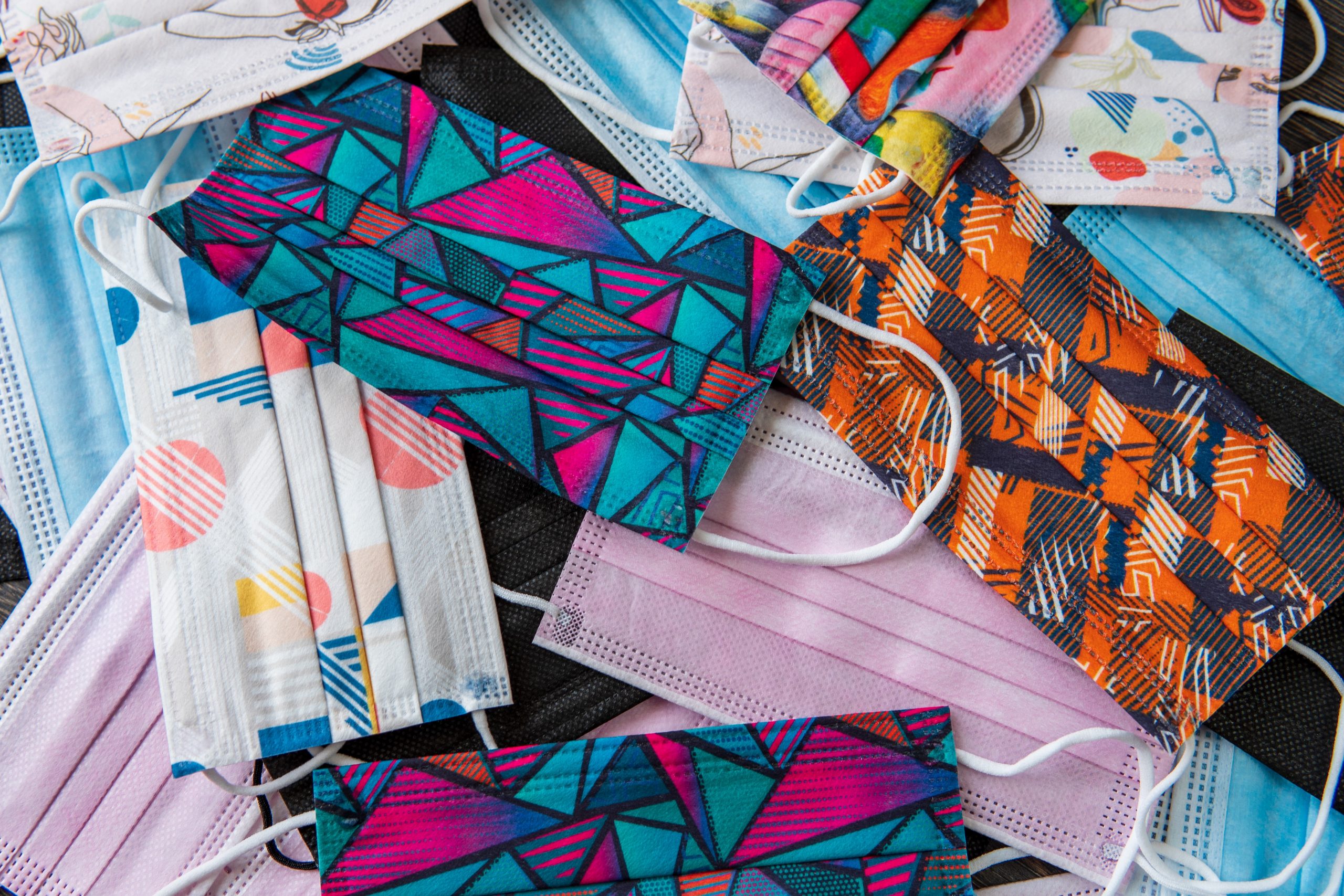 Assorted selection of colour face masks laying on a dark surface.