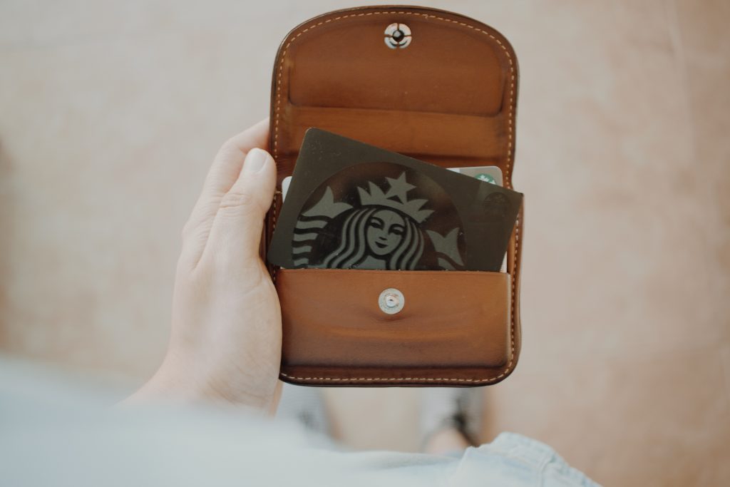 Person's hand, holding a wallet that contains a Starbucks card.