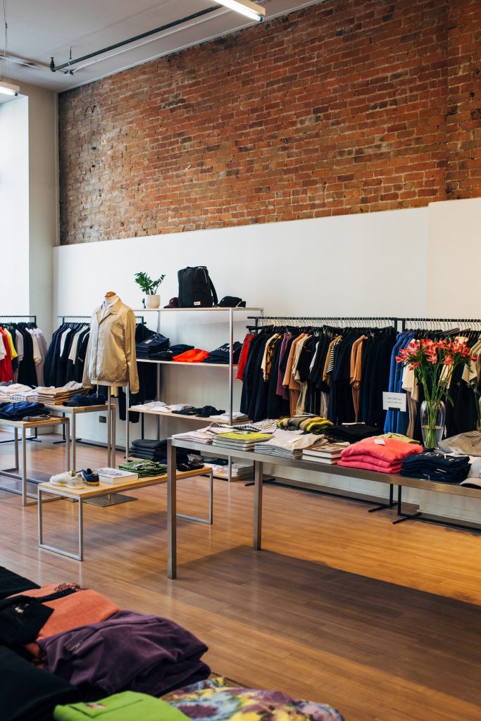 The inside of a retail clothing store where items are neatly displayed on shelves and hung on racks.