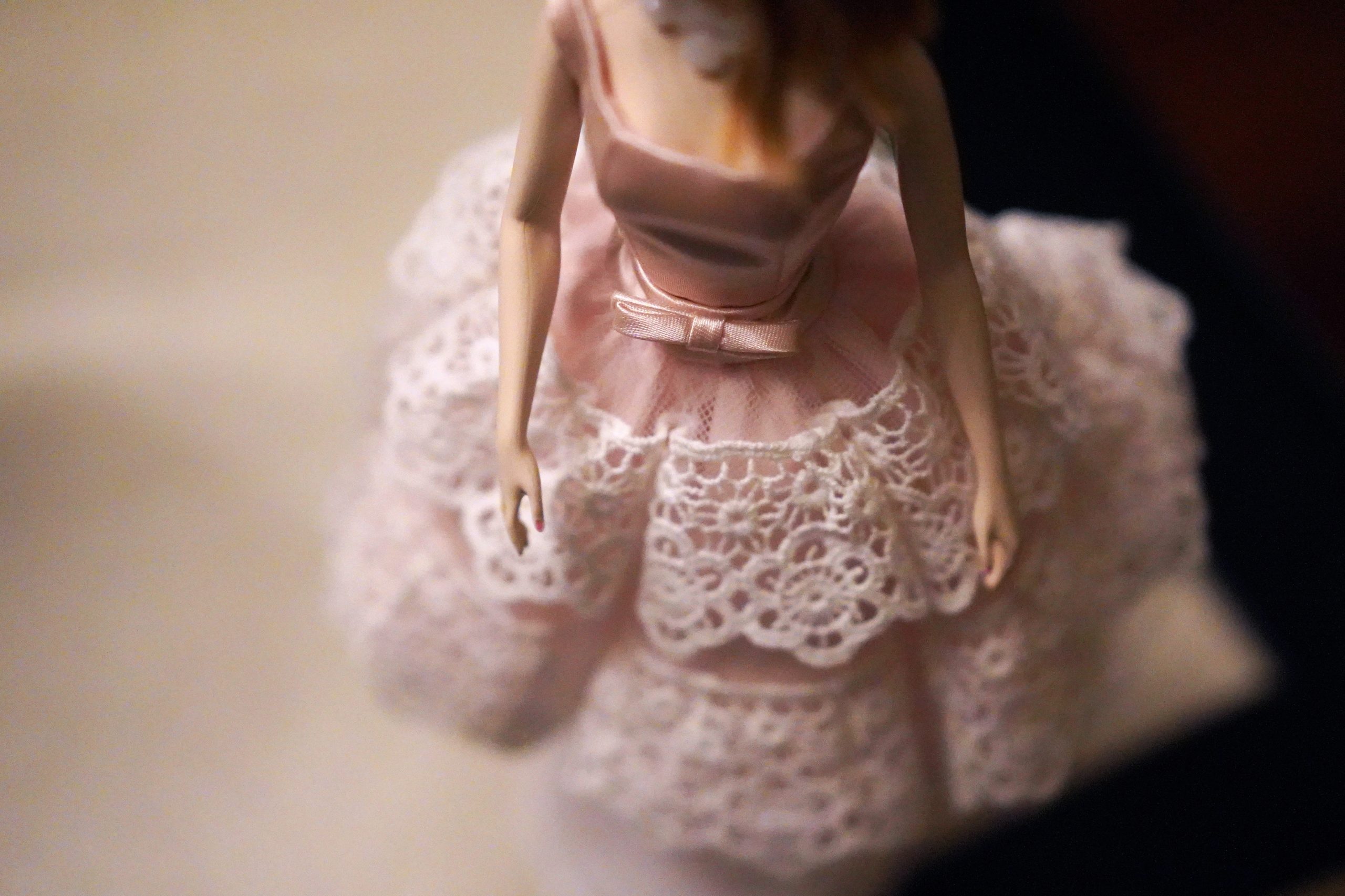Barbie doll figure wearing pink dress with white lace in the skirt portion.
