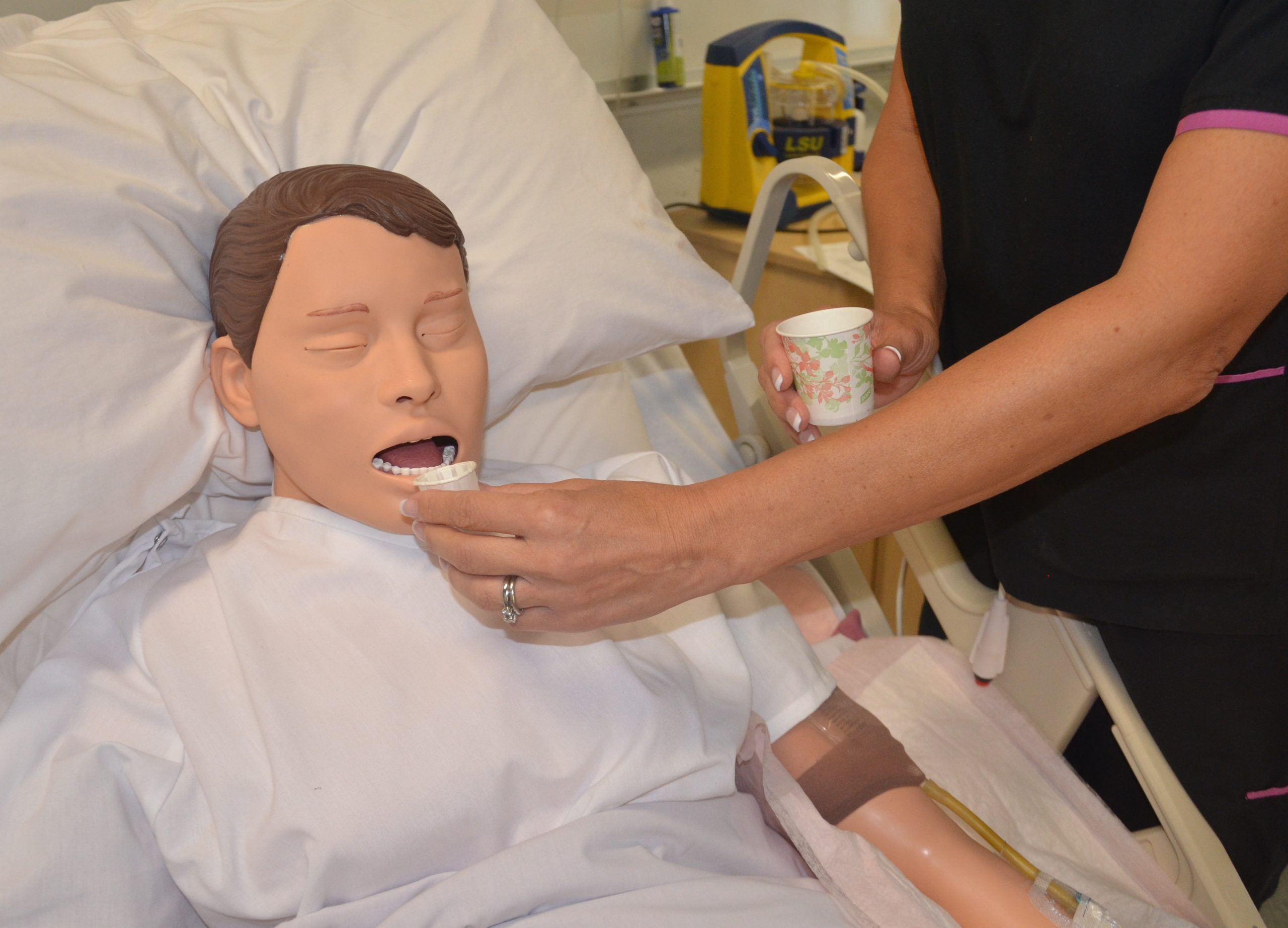 a nurse demonstrates how to adminster oral medication on a medical mannequin