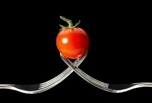 A small tomato held up by two forks