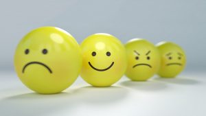 A series of yellow balls with sad, happy, and other emotional faces.