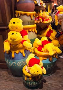 A bunch of Winnie-the-Pooh stuffed animals in toy honey pots.