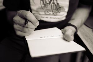 A person writing on a small notepad.