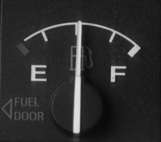 A gas guage with the needle in the middle between empty and full.