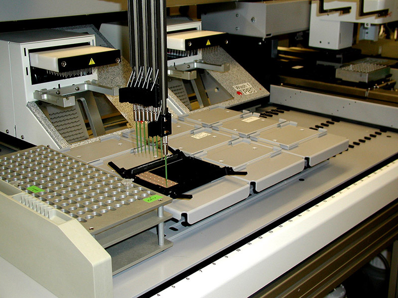Photo shows a protein pattern analyzer. It is a large piece of equipment on a desktop with pipettes at the end of long steel tubes.