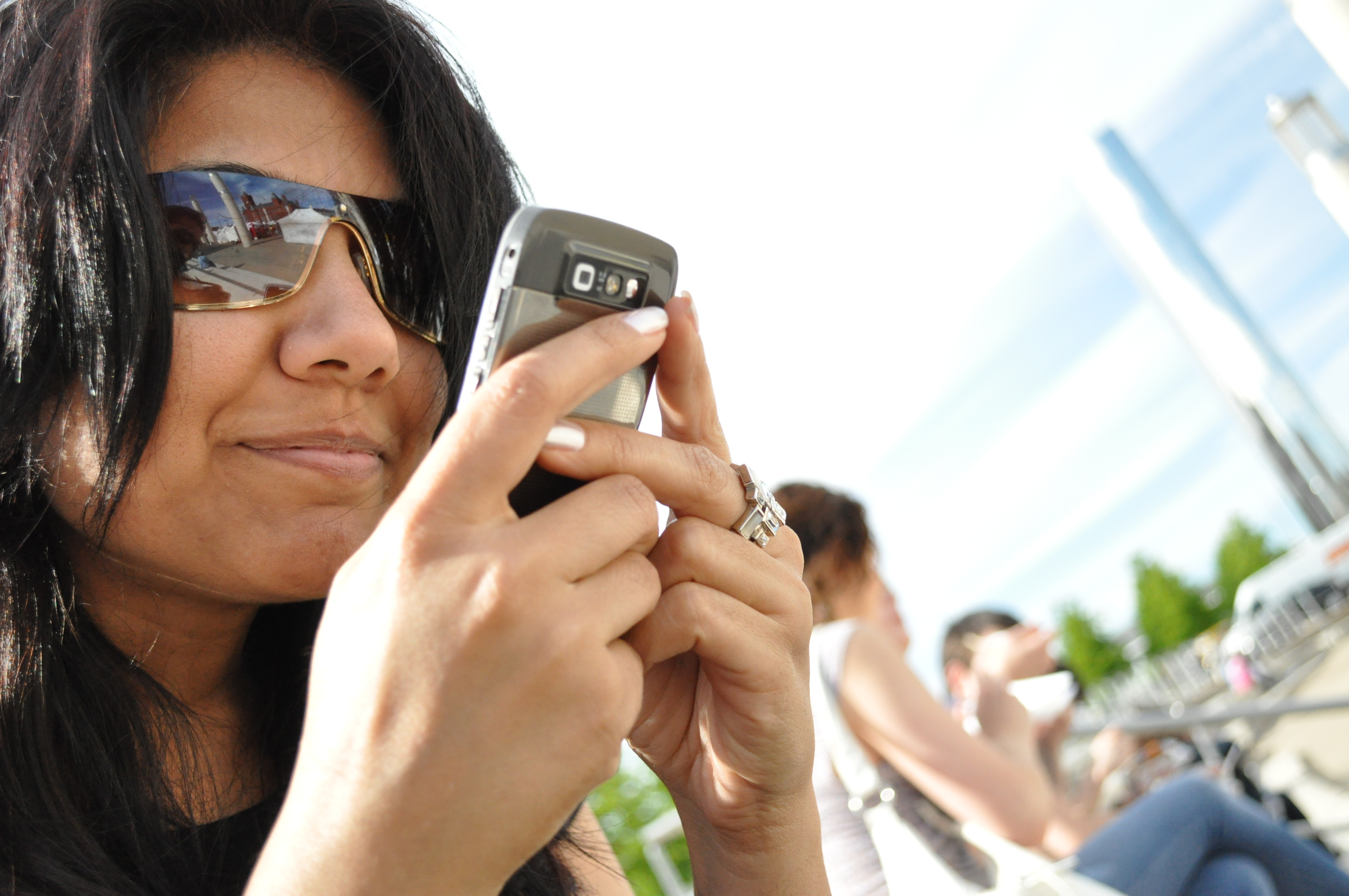 A photo shows a woman holding a phone close to her face as she text messages someone.