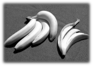 A bunch of four bananas next to the empty peel of another banana.
