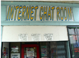 The storefront of a cybercafe with a banner that says "Internet chat room."