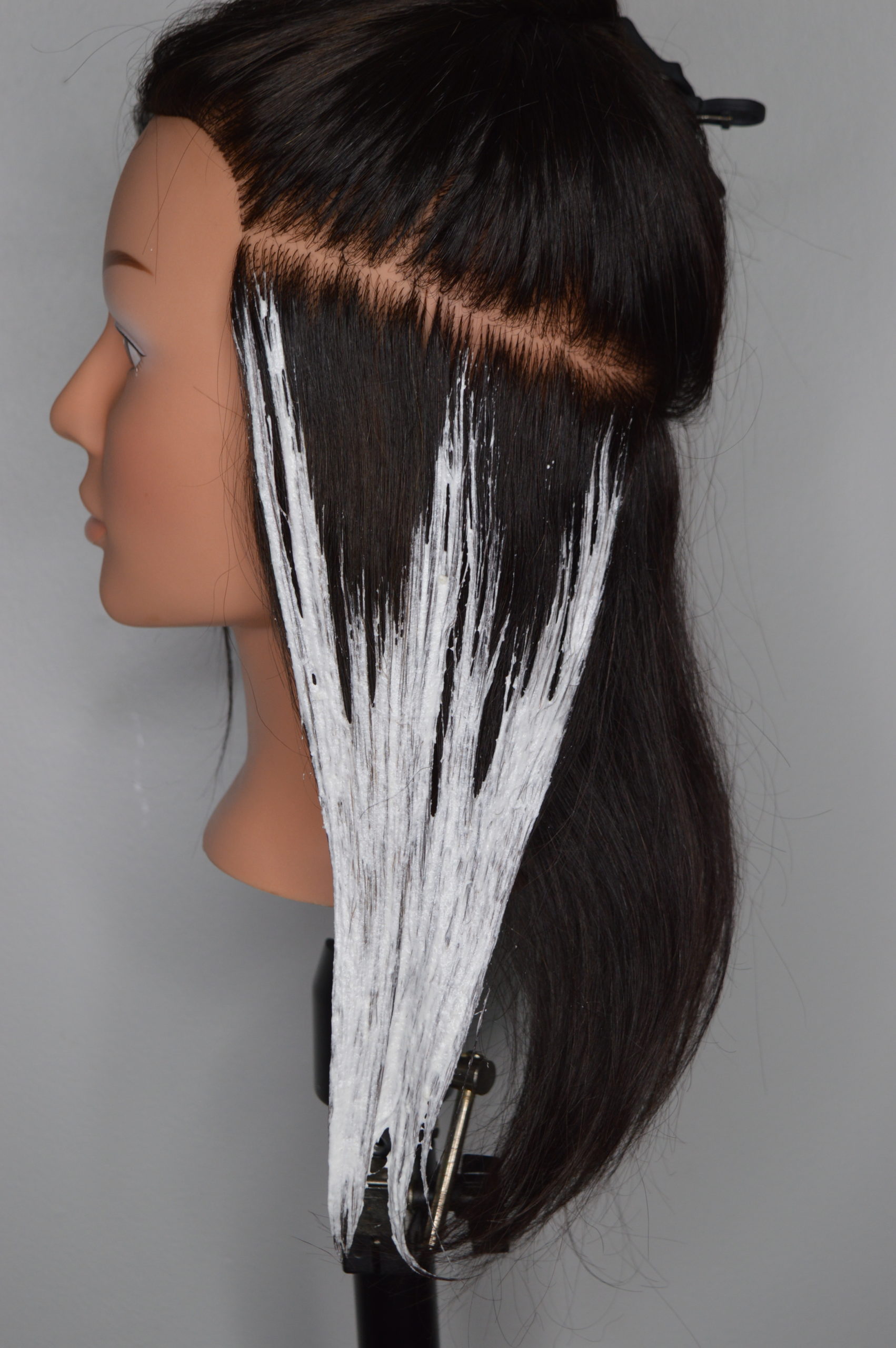 Lightener is applied to a large section of hair to form a W shape.