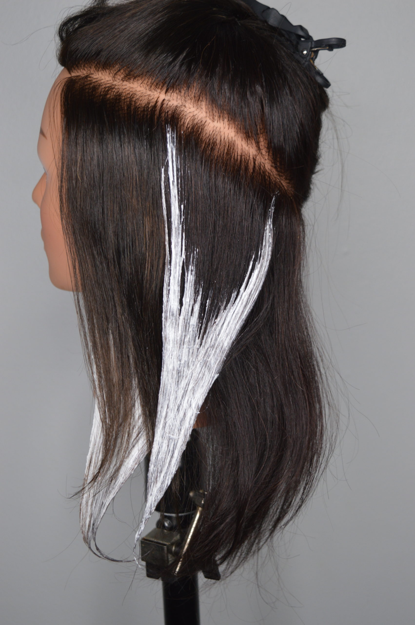 Lightener is applied to a section of hair to form a V shape.