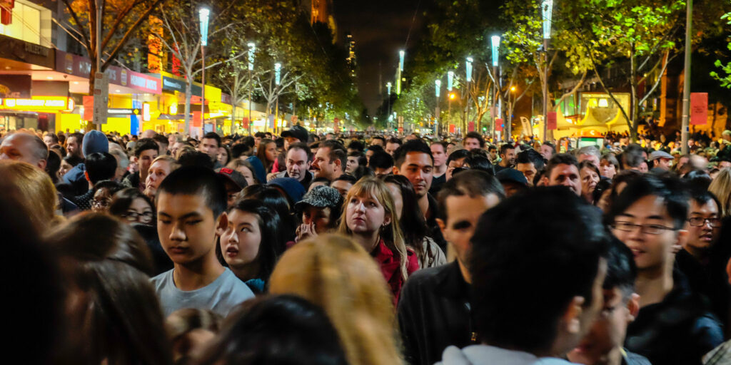 Shoulder to shoulder crowd on a city boulevard at night.