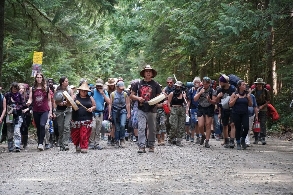 50 to 100 aboriginal and environmentalist protestors marching and drumming on a logging road near Fairy Creek, Vancouver Island.