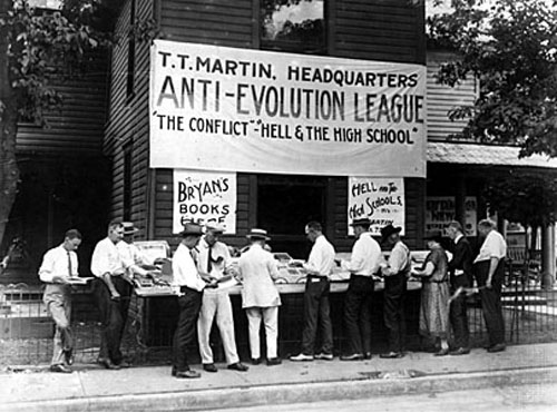 A large sign hangs reading, "Anti-Evolution League, The Conflict - Hell and the High School"