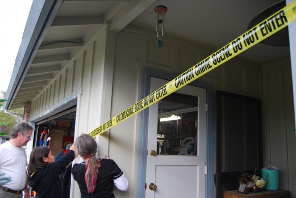 People putting up crime scene tape around a house.