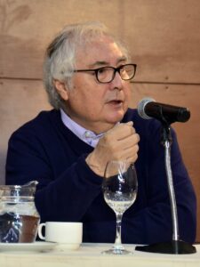 Photo of Manuel Castells in La Paz, Bolivia, seated and speaking into a microphone