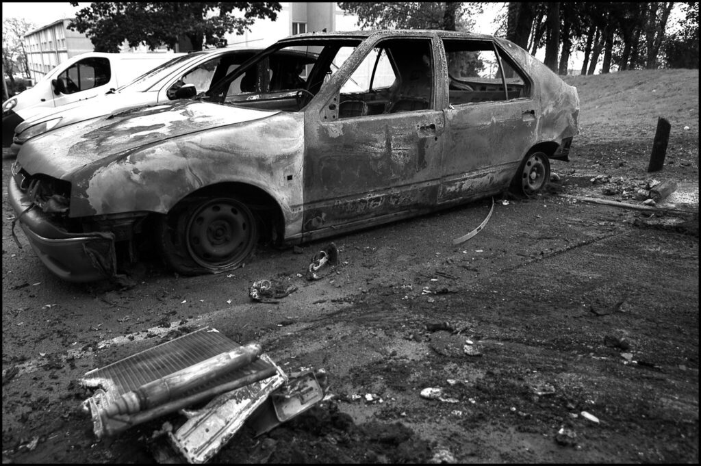 Black and white image of a windowless, scorched car in Paris suburb November 2005
