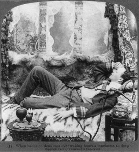 A man laying on a couch of furs beside an opium pipe.