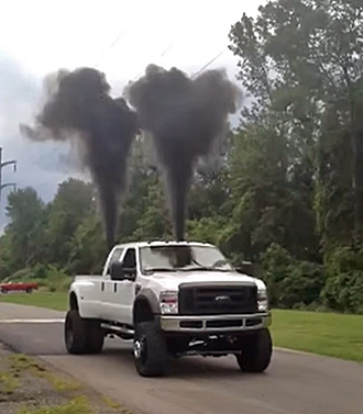 Photo of Ford F-450 with two plumes of thick black smoke shooting up from the rear end.