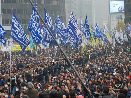 Figure 1.12. People holding posters and waving flags at a protest rally. (photo courtesy of Steve Herman/wikimedia commons)