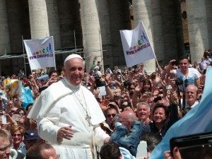 Pope Francis smiles at a surrounding 
crowd.