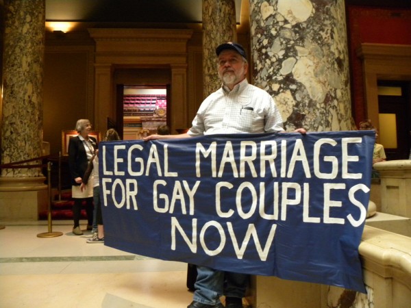 A man holding a sign that says, &quot;Legal marriage for gay couples now.&quot;