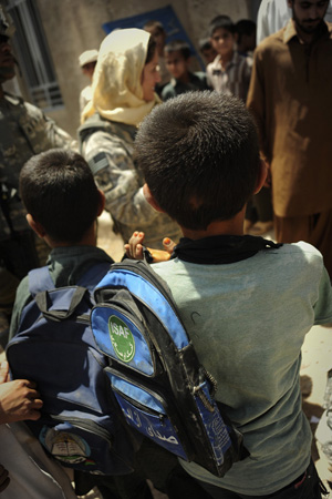 A young boy carrying a backback with an ISAF logo on it.