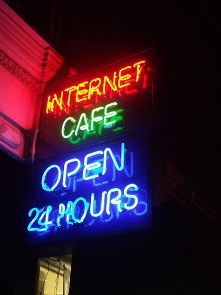 A neon sign that says "Internet Cafe: Open 24 hours."