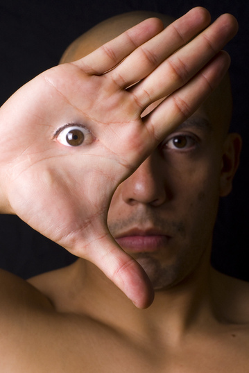 A man holding a hand in front of one eye. The eye is on his hand.