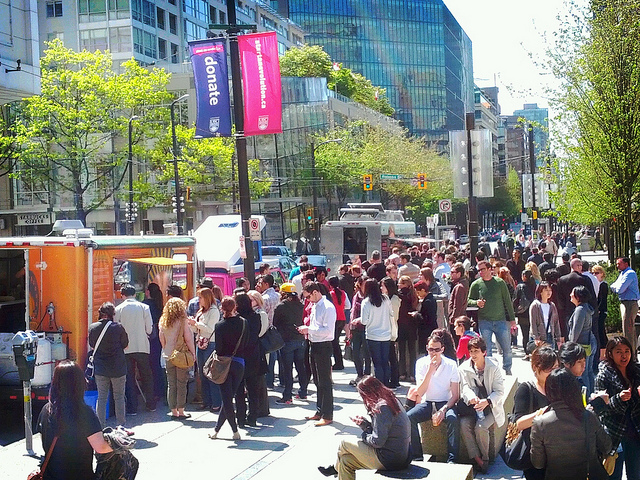 People lined up outside of two food trucks.