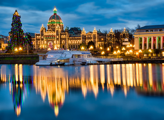 The Parliament buildings covered in Christmas lights at dusk reflect in the Victoria harbour.