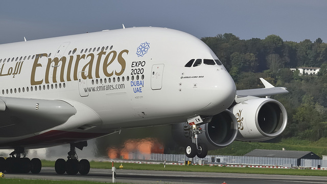 A two-decker plane picks up speed on a runway.