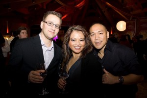 Three people dressed nicely holding wine glasses.